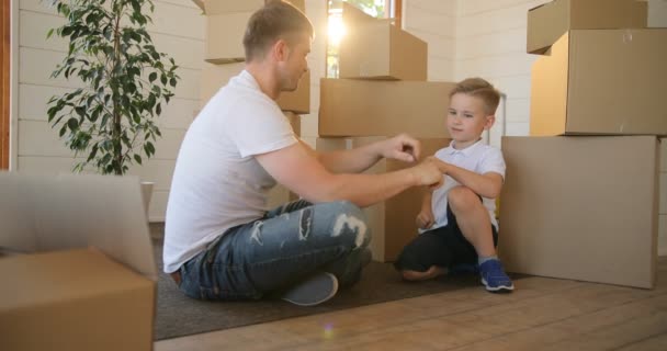 Ritratto di padre e figlio con le scatole backgroud, che giocano insieme nel nuovo appartamento. Ipoteca, trasloco e concetto immobiliare . — Video Stock