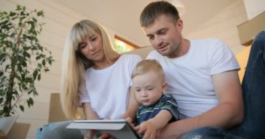 Tablet pc bilgisayar ile mutlu aile portresi. Koca ve karısı ve oğullarının yeni ev içinde hareket. İpotek, insanlar, konut ve gayrimenkul konsept.