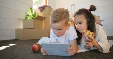 PC tablet ile birlikte oynayan mutlu kardeşler çocuk. Kız ve erkek kardeşim yeni evde tablet birlikte oyun oynamak. Kutuları backgroud