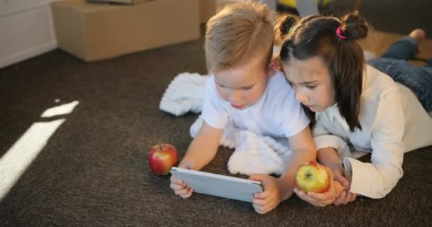 Happy sourozenci dítěte společně pomocí pc tablet. Bratr a sestra spolu hrát v hrách na tabletu v novém domě. Krabice zázemí — Stock video