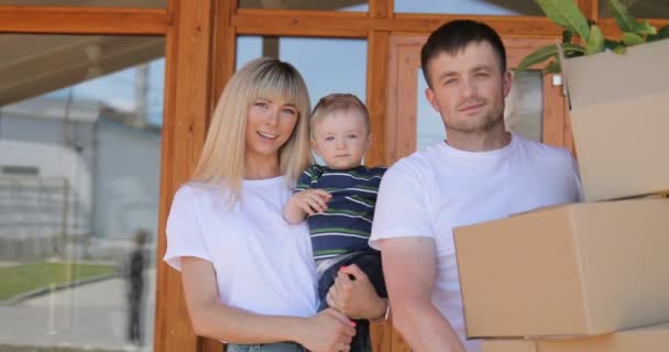 Portrét pár a jejich malý syn, nesoucí lepenkové krabice na stěhování do nového moderního domova. Pár přestěhoval do nového domu domov, nájemné