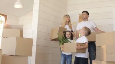Yeni bir eve taşıdıktan aile. Oturma odası için yeni modern ev içine karton kutu taşıyan genç exaciting aile. Yeni evde karton kutular ile mutlu aile