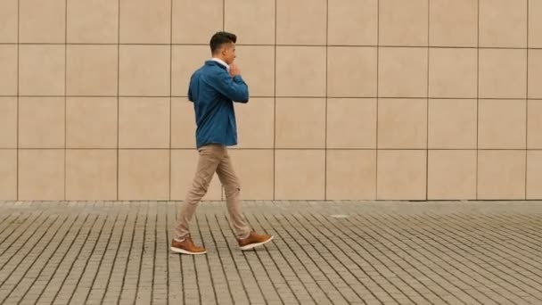 Attractive man listening the music in headphone while walking near the airport. — Stock Video