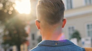 Dönüm, şehir arka plan üzerinde gülümseyen ve kameraya bakarak daha yürüyen genç mutlu adam portresi.