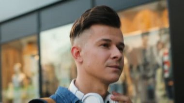 Şehirde sokakta yürürken baş telefonları giyen genç adam portresi.