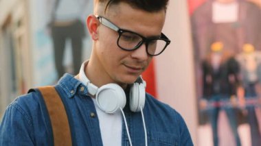 Çekici bir genç adam sokakta arkadaşlarınızla sohbet için cep telefonu kullanarak boyun baş telefon ile şık bardaklarda portresi.