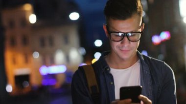 Bina açık renkli üzerinde akşam anda sokakta akıllı telefon kullanarak şık bardaklarda çekici adam.
