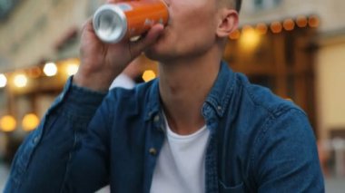 Fanta şehir arka plan şişesinde içme çekici bir adam portresi. Atış kapatın.