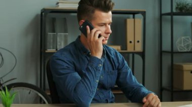 Office arka planda ortağıyla konuşmak için akıllı telefon kullanan genç iş adamı.