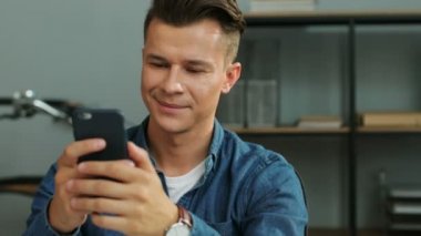 Ofiste otururken akıllı telefon yazarak genç çekici iş adamı. Portre vurdu.