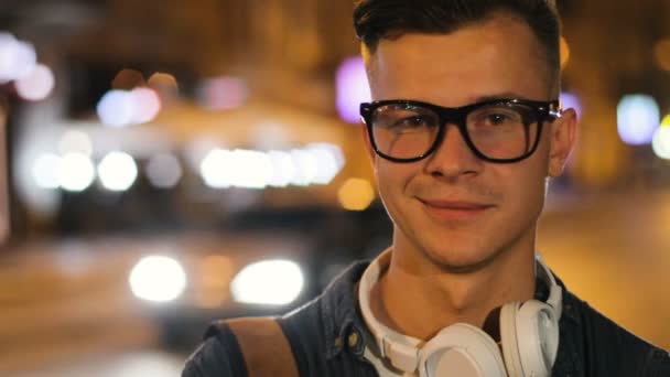 Close up tiro de homem elegante bonito nos óculos com telefone principal no pescoço na cidade à noite . — Vídeo de Stock