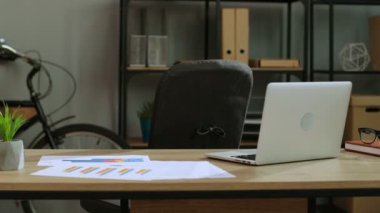 Onun için geliyor rahat tişörtlü çekici adam ofis, tablo ve içinde belgili tanımlık laptop çalışmaya başlayın, oturmak.