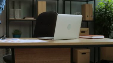 Onun için geliyor rahat tişörtlü çekici adam ofis, gözlük ve içinde belgili tanımlık laptop çalışmaya başlayın.