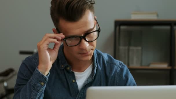 Портрет молодого бизнесмена в повседневной рубашке, работающего в ноутбуке в стильном офисе, чувствующего головную боль . — стоковое видео