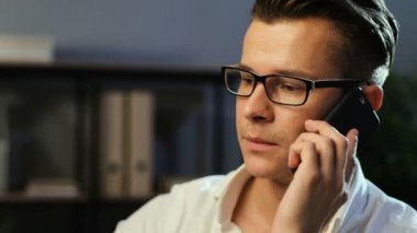 Ortağı bulunan office arka plan iş günü boyunca konuştuğun için akıllı telefon kullanan genç iş adamı.