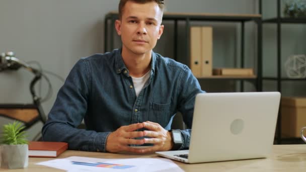 Portret van vertrouwen jonge zakenman in casual shirt op zoek naar de camera in het moderne kantoor. — Stockvideo