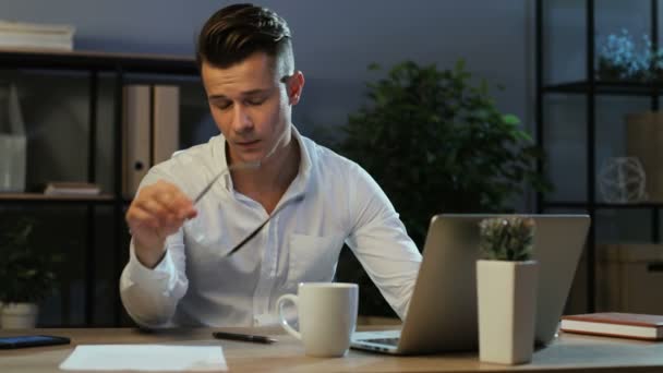 Портрет уставшего бизнесмена в повседневной рубашке, работающего в ноутбуке в стильном офисе, чувствующего головную боль . — стоковое видео