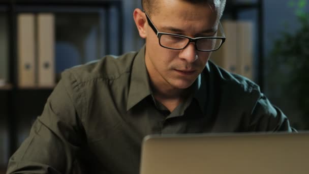 Retrato del joven hombre de negocios guapo con la camisa caqui trabajando en el portátil en la elegante oficina . — Vídeo de stock