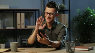 Video çatırdamak ile sokulgan ofiste de akşam için akıllı telefon kullanarak yakışıklı iş adamı.