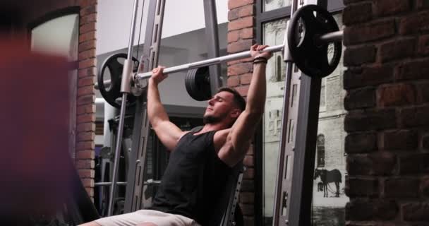 Homme musclé faisant de la musculation dans une salle de gym sombre et ombragée soulevant des poids tenant une haltère. Concept de santé et de fitness — Video