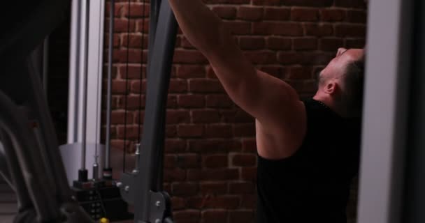 Gespierde man doen crossfit opleiding in een donkere schimmige sportschool tillen gewichten houden een barbell. Gezondheid en fitness concept — Stockvideo