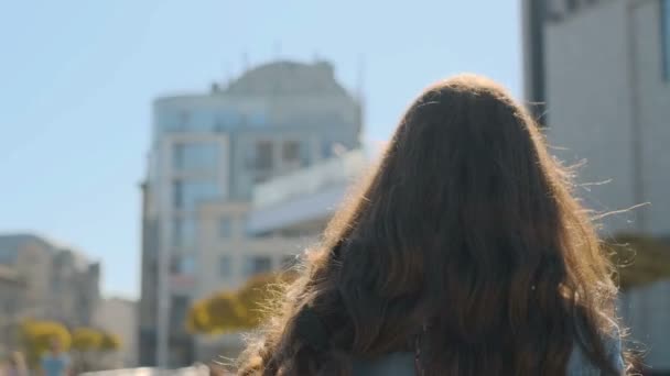 Portrait de jolie adolescente écoutant de la musique sur smartphone pendant la marche jetez la rue d'automne, tourne, regardant vers la caméra et sourit. Urbain, concept de ville — Video