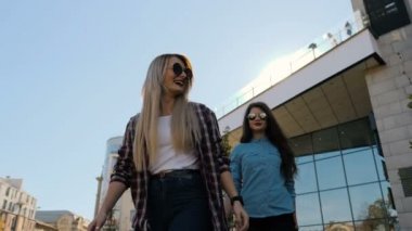 Mutlu genç kız kucaklayan. Veren iki mutlu kız arkadaş omzunda, gülen ve güneşli şehir arka plan üzerinde yürüme.