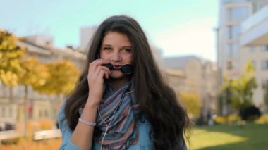 Kulaklık, açık müzik şirin hippi kız portresi kapatın. Kameraya bakarak ve şehir sokak arka plan açık havada gözlükte kapalı alarak genç kız.