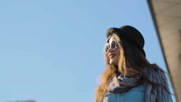 Porträt einer lächelnden Frau mit schwarzem Hut und Sonnenbrille, die in die Kamera blickt. urbanes, städtisches Konzept — Stockvideo