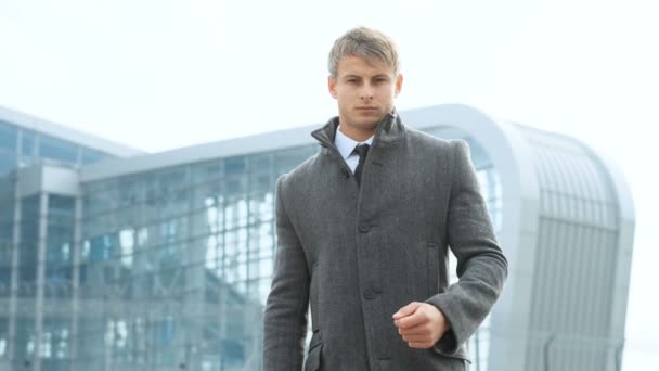 Homme d'affaires sérieux regardant la caméra, comptant de un à trois sur les doigts. Portrait d'homme portant costume et manteau debout près d'un immeuble de bureaux en verre moderne — Video