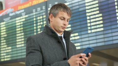 Takım elbise ve ceket uçağını gelenler elektronik tablo arka planda kontrol etmek için akıllı telefon kullanarak ciddi işadamı portresi.