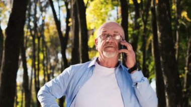 Portre sakal ve gözlük ile smartphone telefon görüşmesi ile komuta sizde. Aramaya cevap vermek için cep telefonu kullanan olgun yaşlı adam. Bağlı kalma