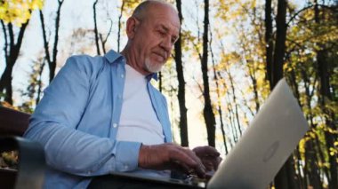 Baba bir bankta oturur ve hir bilgisayar kullanır. Komuta sizde portresi sakalı dizüstü bilgisayar açık kullanarak kapatın