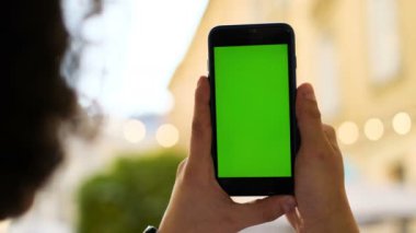 Chroma anahtar yeşil ekran sokak arka planda, yeni teknoloji kavramı ile mobil akıllı telefon tutan adam. Chroma anahtar. Açık. Sokakta duran cep telefonu kullanan adam. Arkadan görünüm vurdu.