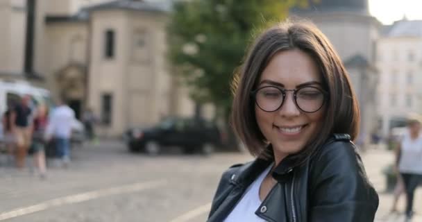 Güzel kız gülümsüyor ve saçlarını sokakta tidies — Stok video