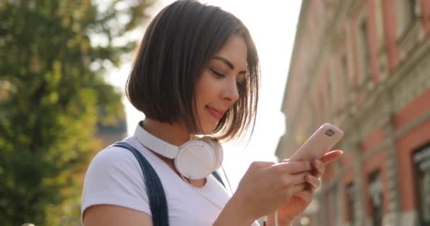 Uma menina está enviando mensagens em seu telefone na rua, close-up — Vídeo de Stock