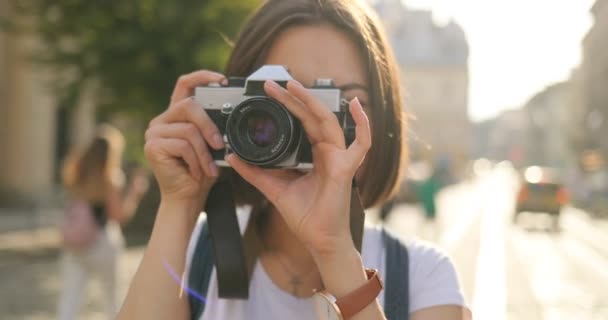 Menina bonita está tirando fotos em uma câmera de filme antigo — Vídeo de Stock