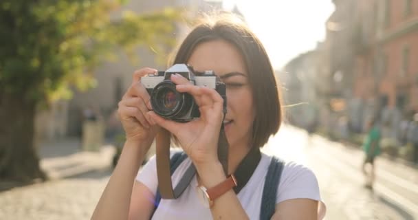 ein Mädchen macht Fotos mit einer Filmkamera und lächelt