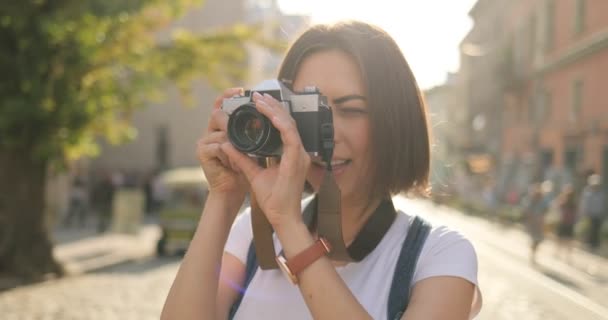 Uma menina está feliz tirando fotos em uma câmera de filme — Vídeo de Stock