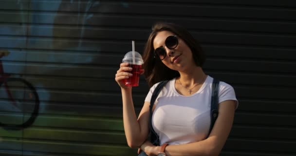 Красивая девушка в солнечных очках держит лимонад — стоковое видео