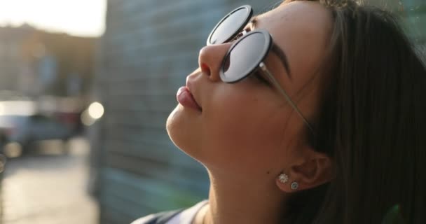 Дівчина в сонцезахисних окулярах дивиться навколо і посміхається — стокове відео