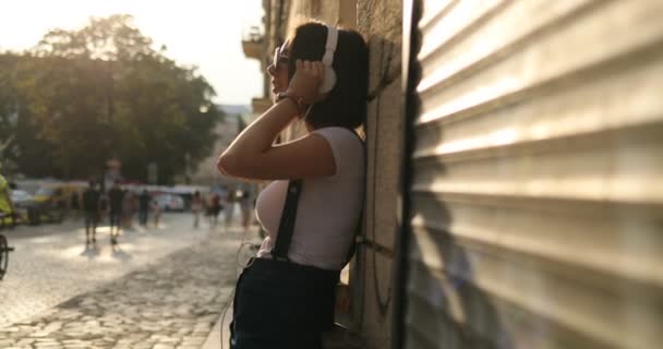 Ένα κορίτσι φοράει τα ακουστικά σε μια ηλιόλουστη ημέρα — Αρχείο Βίντεο