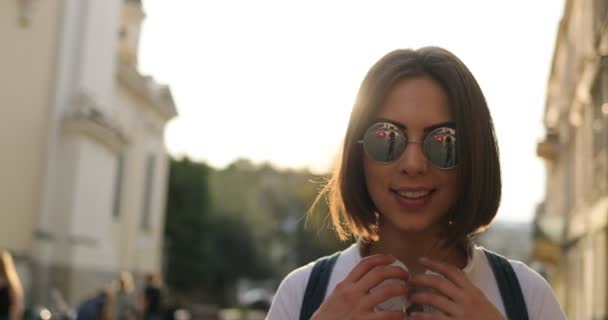 Uma mulher de óculos de sol está sorrindo e usando fones de ouvido — Vídeo de Stock