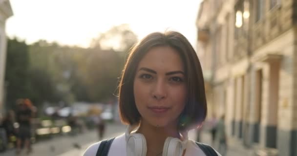 Uma morena bonita em fones de ouvido está usando óculos — Vídeo de Stock