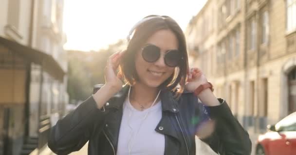 Дівчина в навушниках танцює на вулиці — стокове відео
