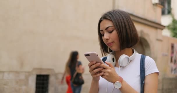 Una chica sonriente está caminando y respondiendo a un mensaje — Vídeo de stock