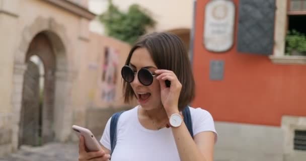 Una chica está emocionada mirando su teléfono y saltando — Vídeo de stock