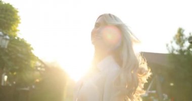 Şehir merkezinde, çekici genç bayan döner kamera ve gülümsüyor. Sokakta yürüyen mutlu gülümseyen sarışın kadın portresi. Geri görüntülemek, dönüm, kamera ve gülümseyerek mutlu bir şekilde bakarak bir kadın