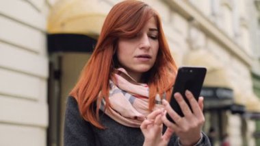 Çekici zencefil kadın kentsel street yürüyüş sırasında cep telefonu kullanarak. Alışveriş, indirim alma Bayan portresi akıllı telefon e-posta kutusunu kontrol. Urban, sokak, yaşam biçimi