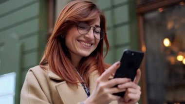 Gülümseyen kadın eski şehrin sokaklarında yürüyüş sırasında cep telefonu App kullanarak. Kadın mesaj ile cep telefonu, cep telefonu kısa mesaj yazarak. Portre portre, yaşam tarzı, kentsel, bokeh.